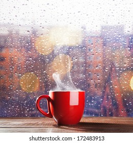 Steaming cup of coffee over a cityscape background