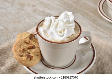 A Steaming Cup Of Hot Chocolate With Whipped Cream And Chocolate Chip Shortbread Cookies