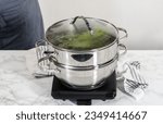 Steaming fresh asparagus in stainless steel steaming pot.