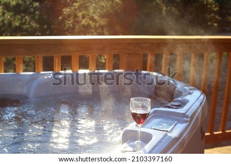 Steaming hot tub on the deck with wine glass
