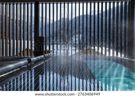 A steaming outdoor infinity pool meets vertical slats at a Dolomites spa, facing a snowy alpine valley, chalet roofs, pine slopes, and distant peaks in winter.