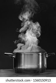 Steaming pot on black background. Smoke above boiling soup pot. 