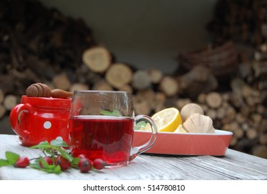 Steaming Rose Hip Tea, Rose Hip, Lemon, Honey On Rustic White Table In Exterior And Wooden Lemon Squeezer, Red, White Potted Bowl, Horizontal, Wider