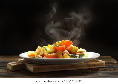 Steaming of Stir chicken with vegetables, cucumber, red bell pepper, tomato, onion and chicken. Thai dish sweet and sour sauce fried with smoke on dark background on wooden cut board.  - Powered by Shutterstock