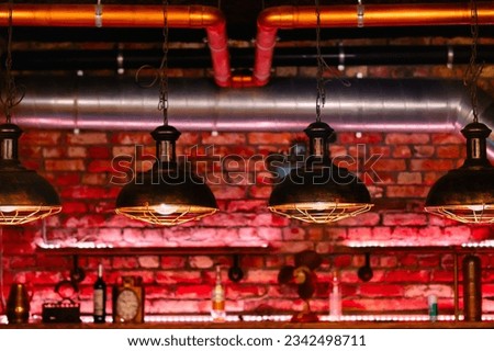 Steampunk style design element unusual lamps hanging in a row view over red brick wall inside cafe or restaurant
