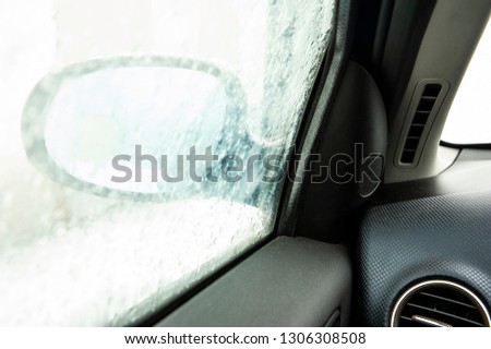 Steamy car window makes it difficult to look in the car mirror. Winter cold day.