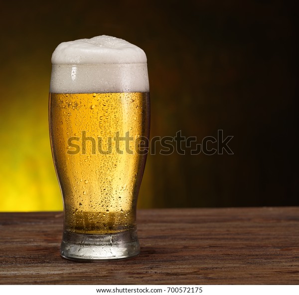 Steamy glass of beer on the wooden table.