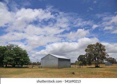 Steel barn on a farm with cloudy blue sky.