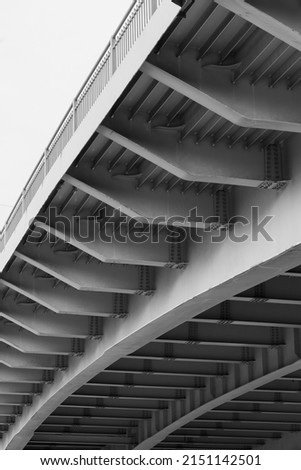Steel bridge span construction, bottom view with gray girders, vertical black and white photo