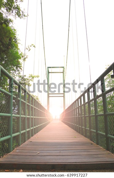 Steel bridge with wood floor ,rope bridge under\
the sunset lighting