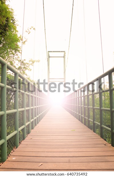 Steel bridge with wood floor ,rope bridge under\
the sunset lighting