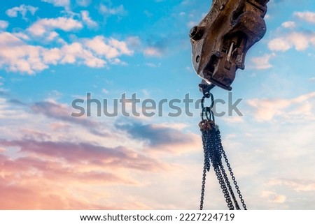 Steel chain attached to the excavator's arm. Lifting gear against blue sky with space for text as an abstract industrial background