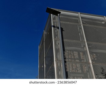 steel cladding of a building with a expanded metal lattice structure. galvanized gray nets protect the industrial building. Blue sky in contrast to a silver background - Powered by Shutterstock