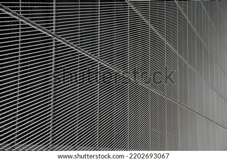 steel cladding of a building with a expanded metal lattice structure. galvanized gray nets protect the industrial building. Blue sky in contrast to a silver background, wall