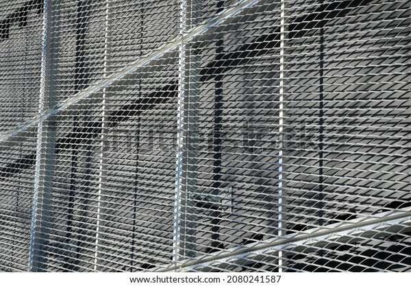 steel cladding of a\
building with a expanded metal lattice structure. galvanized gray\
nets protect the industrial building. Blue sky in contrast to a\
silver background