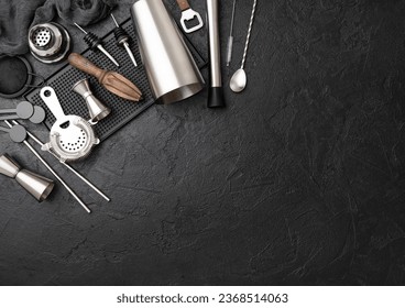Steel cocktail shaker,strainer,jigger and wooden juicer with muddler on black rubber tray with spoon and silver straw.