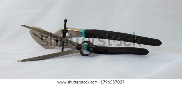 Steel compass for drawing and\
measuring with a pair of pliers on a white background. Hand\
tools.