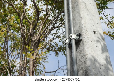 Steel conduits mounted on concrete light poles at the parking lot.