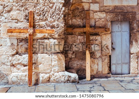 A steel door and two big christian wooden crosses lean against stone wall of the Church of the Holy Sepulchre in Old City of Jerusalem, Israel. Via dolorosa. Jesus christ