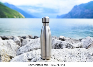 Steel eco thermo water bottle on the background of the lake in the mountains.  Clean and healthy water. Be plastic free. Zero waste.