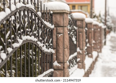 Steel fence combined with stones. Covered by snow.