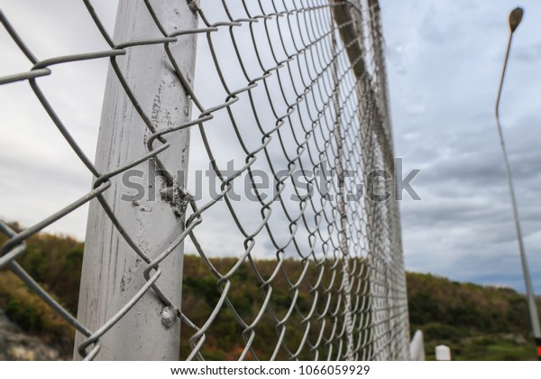 Steel fence protects\
people climbing into water-power stations. Concept of imprisonment.\
Chain Link Fence.