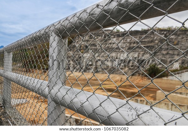 Steel fence protects\
people climbing into water-power stations. Concept of imprisonment.\
Chain Link Fence.