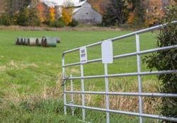 Steel Gate With A Private Property Sign, And A Farm Background In Rural Québec, Pontiac Region.