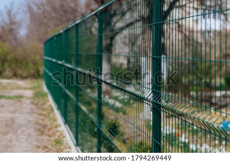 Steel grill. Green fence with wire. Fencing.