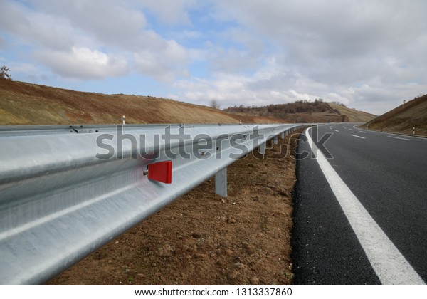 Steel guard rail barrier on the motorway with\
reflective red sign