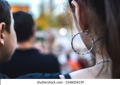
steel hoop on woman's ear with black hair and chain on her neck