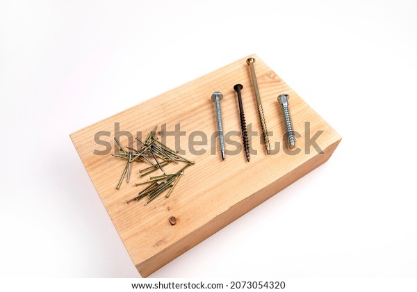 Steel nails on\
a white background. Steel nails lie on a wooden block. Still life\
from tools. High-quality renovation of apartments or houses. The\
choice of material for\
repair