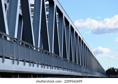 steel railway bridge closeup. diminishing perspective view. blue sky with white clouds. truss girder beams with triangular shaped members. structural design and engineering concept. structural design.
