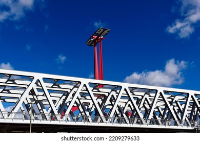 steel railway bridge closeup in perspective view. red steel tower with solar panels. blue sky with white clouds. truss beams with triangular shape members. structural design and engineering. 