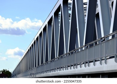 steel railway bridge girder closeup in perspective view. blue sky with white clouds. truss beams with triangular shape members. structural design and engineering. diminishing perspective.