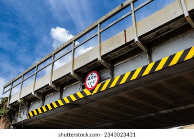 Steel railway bridge over a road from a low angle with a sign displaying a height restriction of 4 metres or 13 and a half feet - Shutterstock ID 2343023431