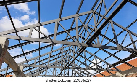 Steel roof structure for building construction. Metal roof structure of a building under construction on a blue sky background with white clouds. Selective focus - Shutterstock ID 2138586229