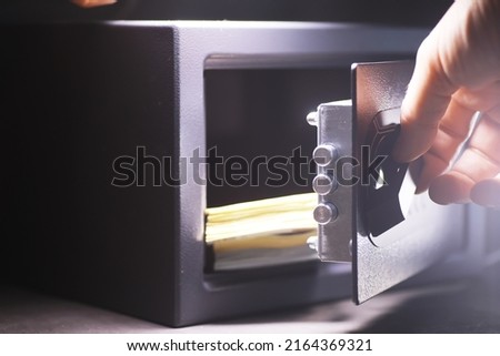 Steel safe with money. Hand putting password in the safety money box in hotel room