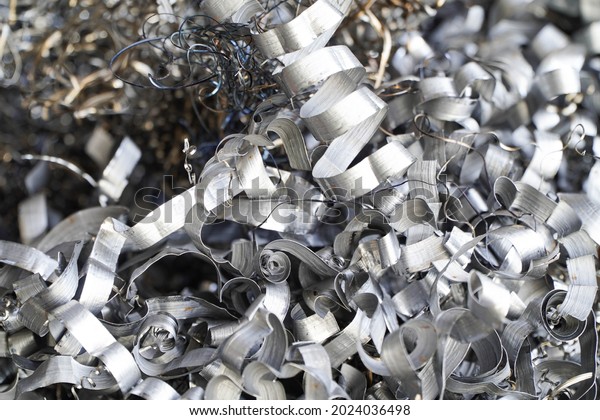 Steel scrap materials\
recycling. Aluminum chip waste after machining metal parts on a cnc\
lathe. Closeup twisted spiral steel shavings. Small roughness\
sharpness,