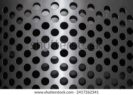 A steel sheet with small round holes. A background for use as an industrial texture. Close up.