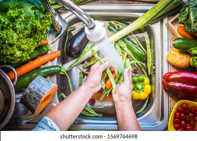 A steel sink filled with water and fresh vegetables to wash. Eat healthy to stay in shape - Powered by Shutterstock