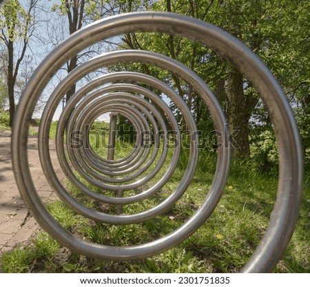 Steel (stainless steel), spiral device for parking (fastening) bicycles. Bicycle parking in the park on a May day. View of the spiral weave of steel tubes.  