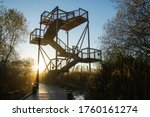 Steel tiered sky tower rising to give panoramic views over the reedbed wetland. Early morning with the low sun flaring onto the boardwalk. Platform, wildlife watching, Leighton Moss nature reserve, UK