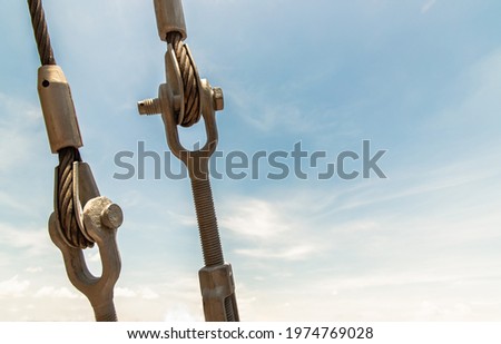 Steel turnbuckle and sling steel or Steel Wire Rope Sling and metal cable clamp connected with screw bolt. Device for adjusting the tension or length of cable on a blue sky background. Copy space.