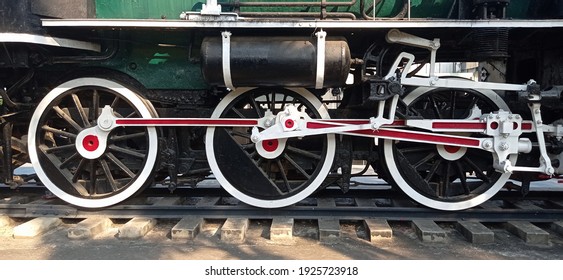 The steel wheel of an old steam locomotive is parked.
