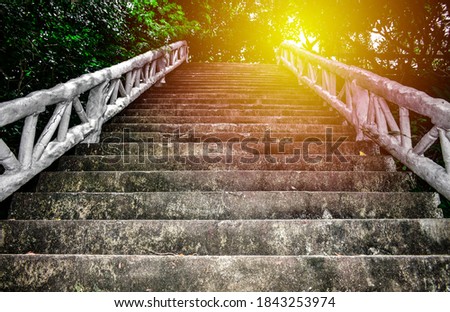 Steep concrete stairs with beautiful sunlight at above. Old grunge staircase with white handrail among green trees at Lad Koh view point. Attraction in Samui Island, Thailand. Up stair in the morning.