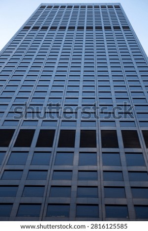 A steep low-angle view looking straight up a towering dark glass and steel corporate skyscraper.