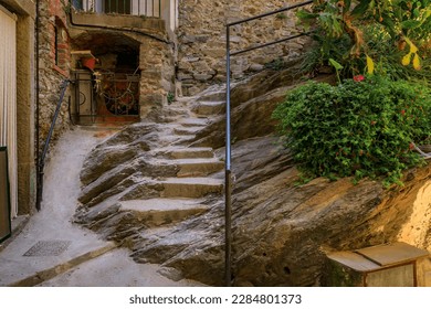 Steep narrow stairs between traditional old terracotta houses on an old town street of Riomaggiore in Cinque Terre on the Mediterranean Sea, Italy
