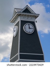 A steeple with 4 clock faces on a bright sunny blue sky and white clouds day.