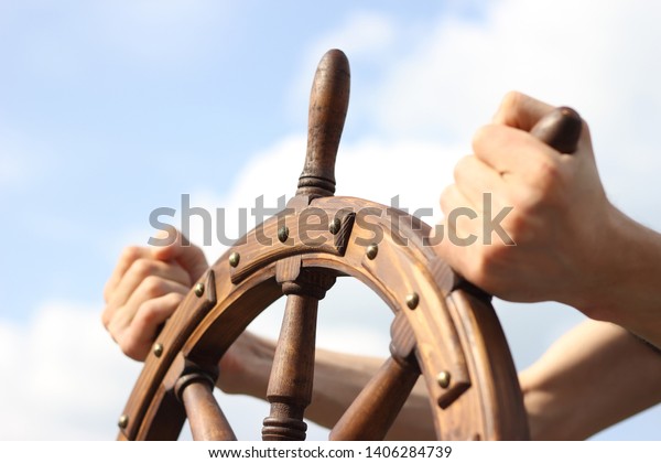 Steering hand wheel ship on sky background, hand
hold hand wheel